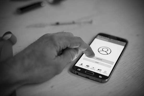 A person interacts with the Second Chance mobile app, activating the "monitor" function before using opioids
