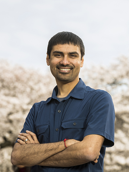 Shwetak Patel pictured in front of cherry tree blossoms