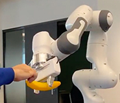 Person handing robot arm a banana