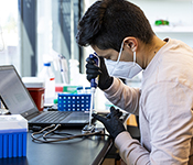 Person wearing mask piping material onto a nanopore reader connected to laptop