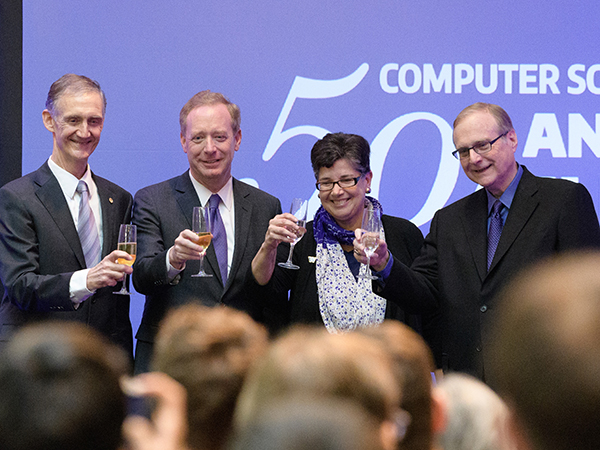 Ed Lazowska, Brad Smith, Ana Mari Cauce and Paul Allen onstage toasting with champagne glasses in front of an audience