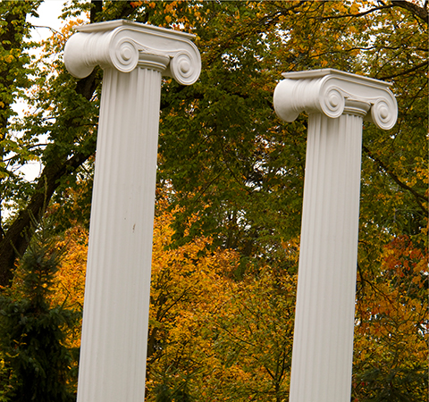 Two Greek columns of UW's Sylvan Grove surrounded by fall foliage and evergreen trees