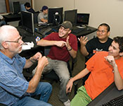 Richard Ladner conversing in sign language with three students in a computer lab