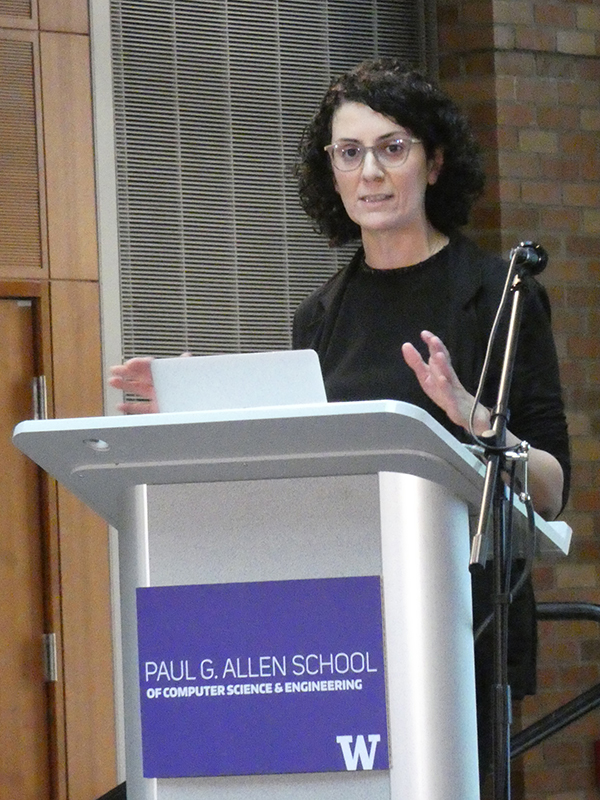 Hannaneh Hajishirzi speaking at a podium displaying the Paul G. Allen School logo and UW block W logo