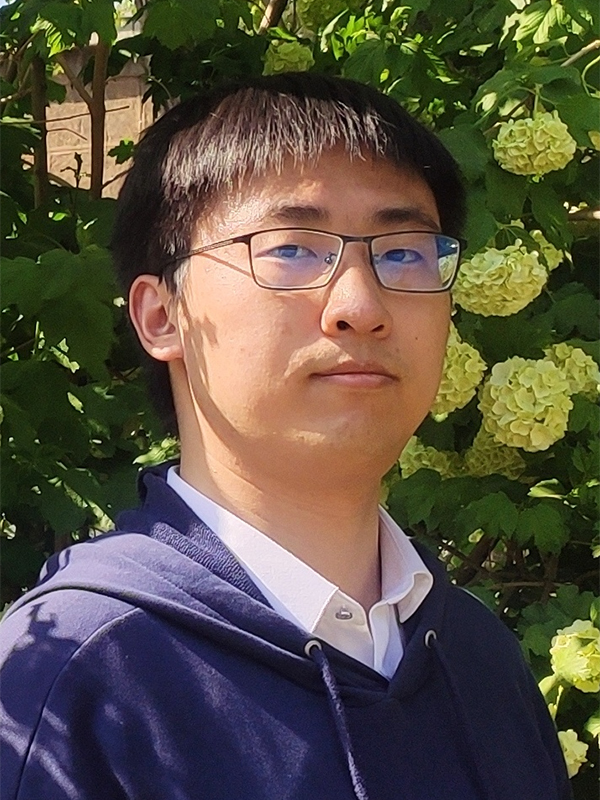 Portrait of Zihao Ye on a sunny day posing in front of pale green hydrangeas with deep green foliage.
