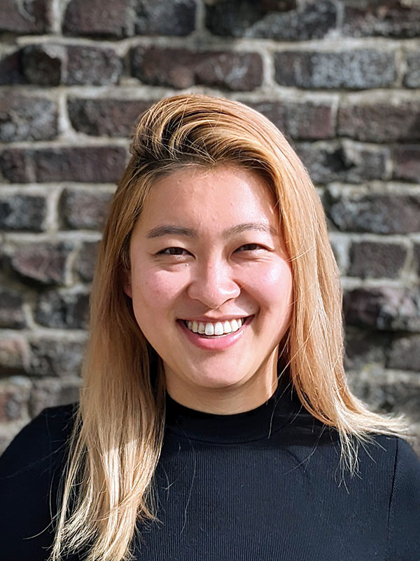 Headshot of Miranda Wei wearing a black sweater against a brick background