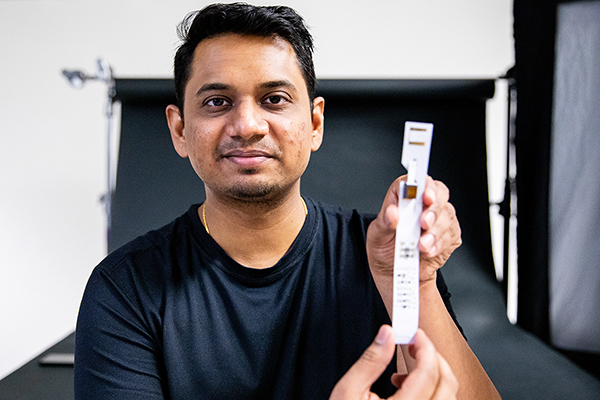 Anandghan Waghmare holds up a glucose test strip modified with additional sensors and other electronic components