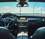 Black leather interior of a car with blue skies through the windshield.