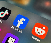 A close-up image of various social media icons including Reddit, Facebook and TikTok on a smart phone.