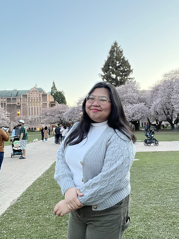 Allen School undergraduate student Czarin Dela Cruz poses among the cherry blossoms in the University of Washington's Quad.