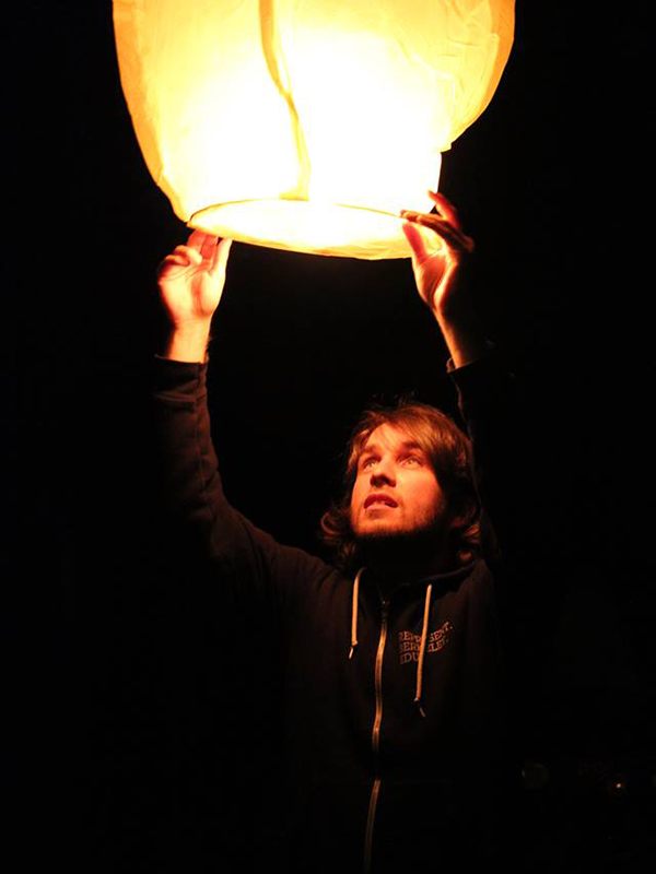 Allen School professor Kurtis Heimerl holds a glowing lantern above his head, illuminating his face.