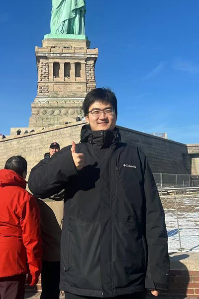 Kaiyuan Liu posing with the Statue of Liberty in the background.