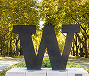 The University of Washington North campus bronze "W" stands against a background of autumn foliage.